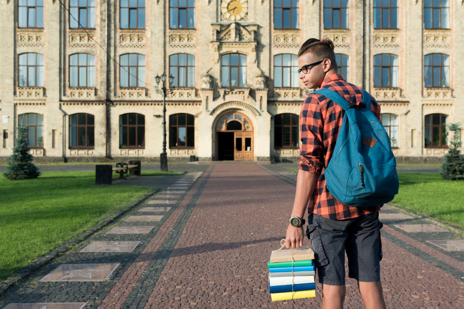 STUDENT HOLDING BOOK STANDING INFRONT OF UNIVERSITY IN UK